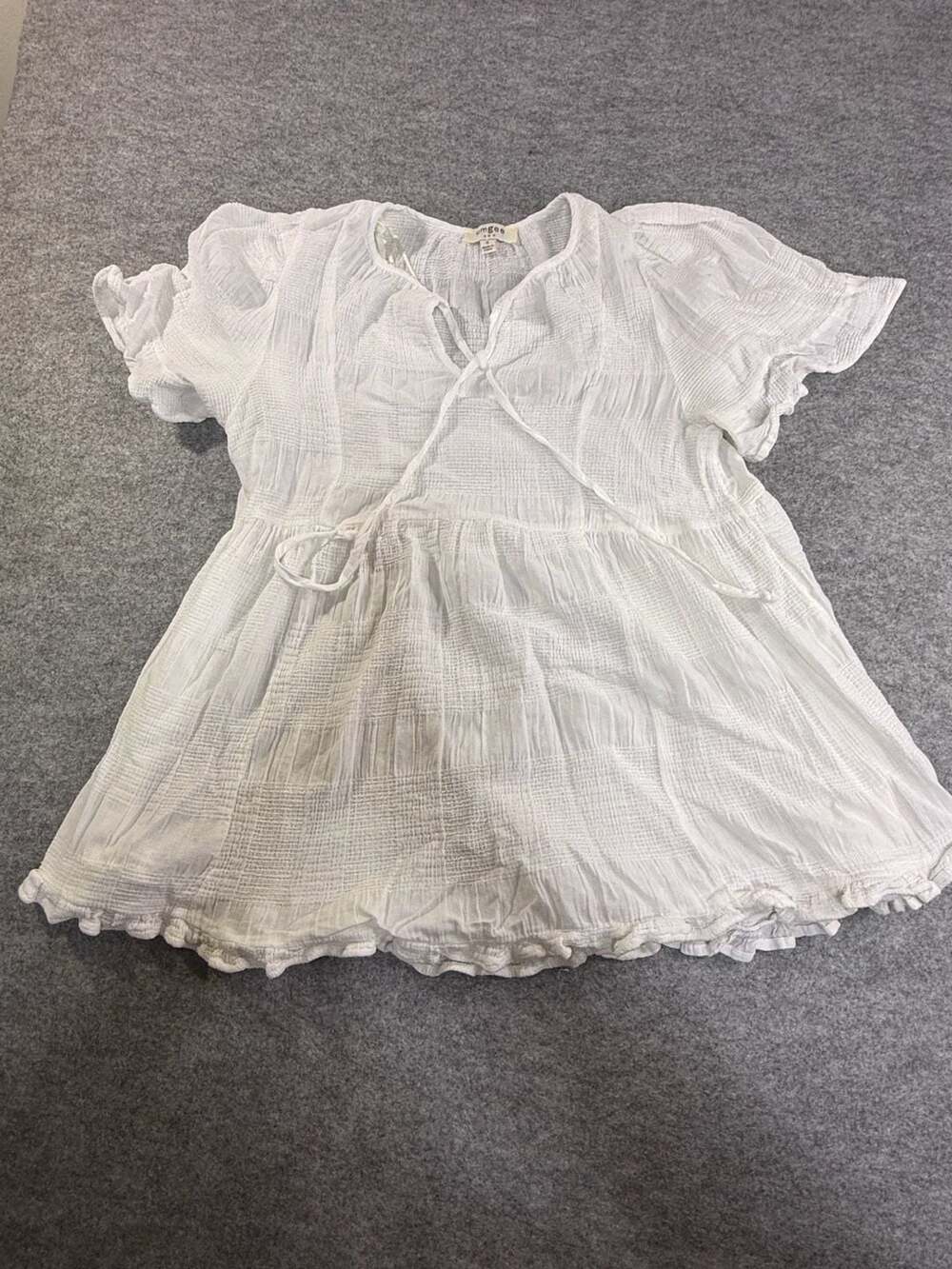 Umgee USA Women's White Textured Babydoll Blouse with Tie Neck and Ruffle Hem